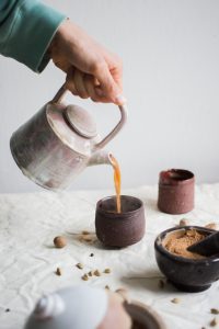 Foto de uma mesa posta e um café sendo despejado em uma xícara.