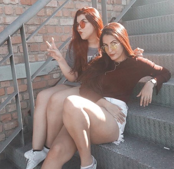 Duas amigas sentada em um escada posando para a foto