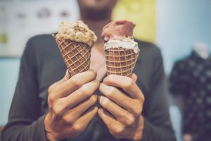 Foto de uma pessoa segurando duas casquinhas de sorvete