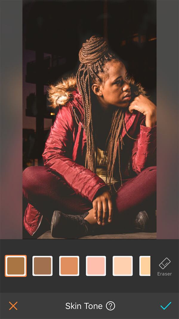 woman with braids in red jacket and pants sits in front of dark city background