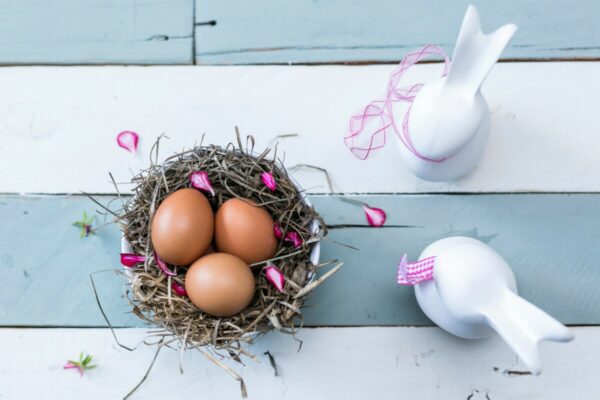 Foto de uma cesta com ovos e coelhos de cêramica do lado
