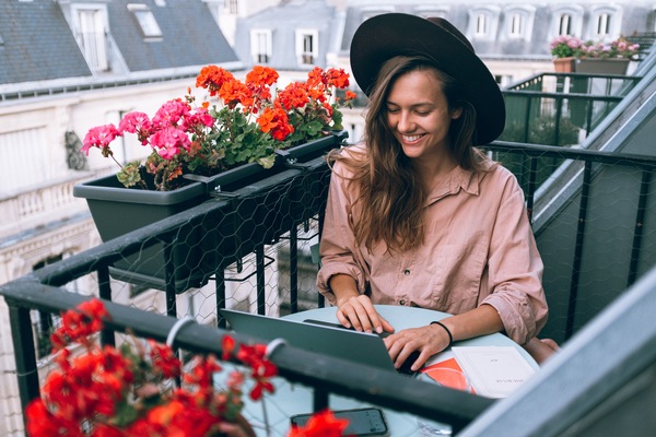 mujer rubia con sombrero trabajando en un balcón en Paris
