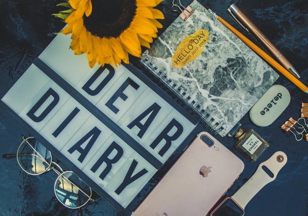flat lay of sign, phone, watch, notebook and sunflower