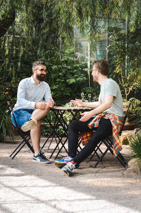 two men sitting at a table in a garden