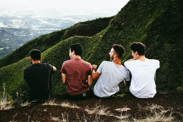 four men sitting on top of a mountain