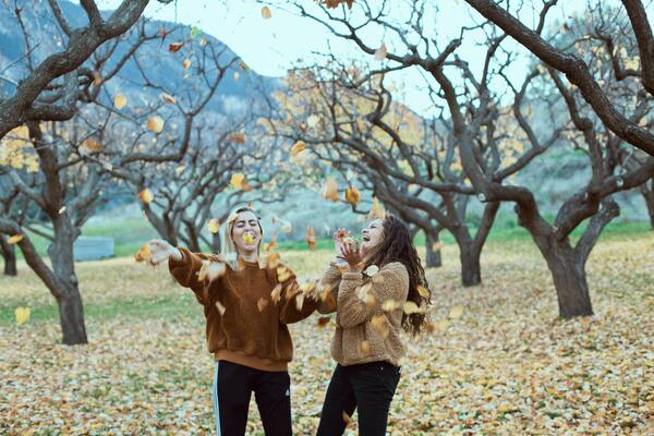 two women playing with fall leaves