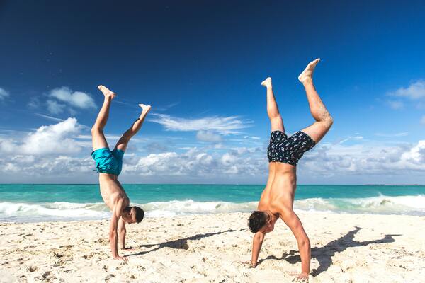 two men doing hand stands on the beach
