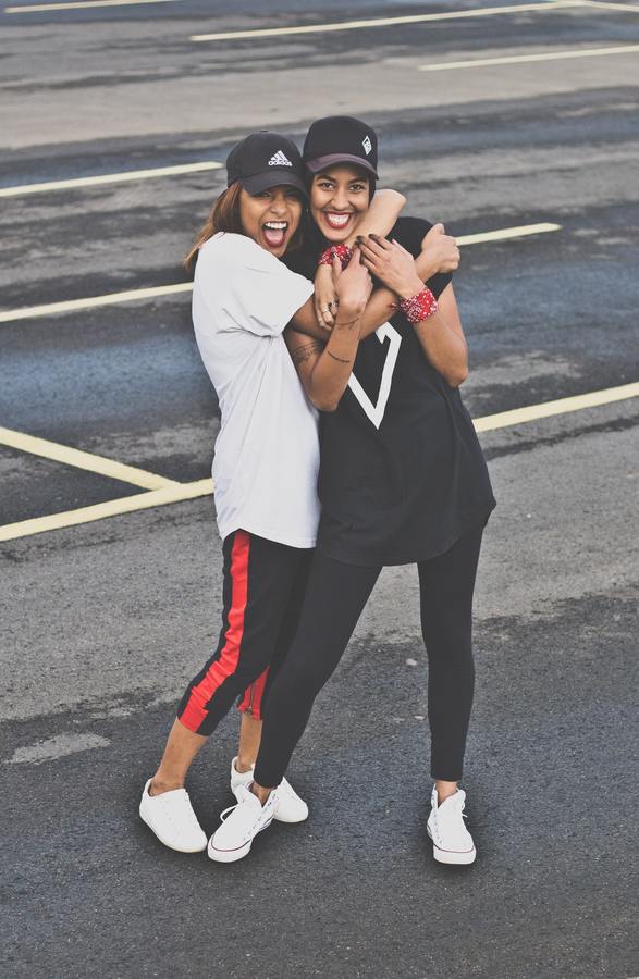 two friends in leggings and t-shirts hugging in the street