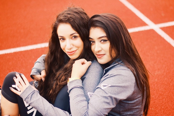 color photo of two women hugging on a red surface