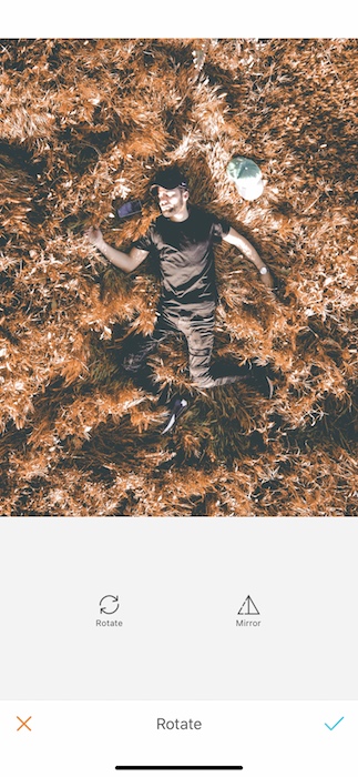 Picture of a guy lay down in a dry grass being edited by AirBrush with the Rotate Tool