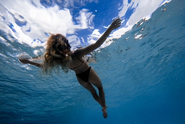 woman in black bikini floating in clear water