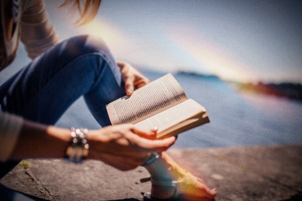 persona leyendo un libro en la orilla del mar