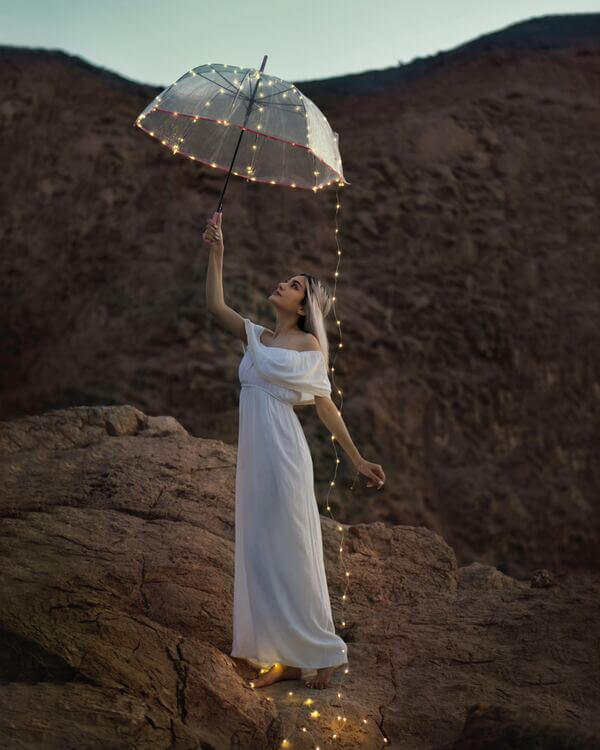 mujer con vestido blanco, paraguas y luces