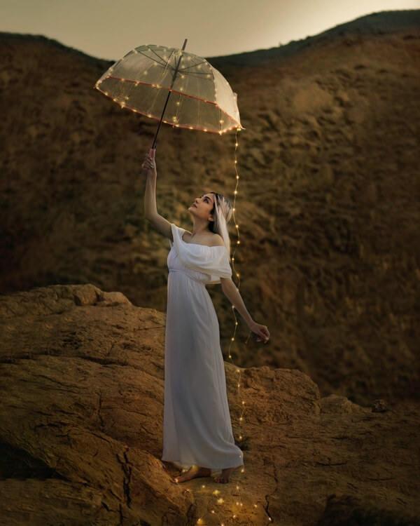 mujer con vestido blanco y paraguas transparente