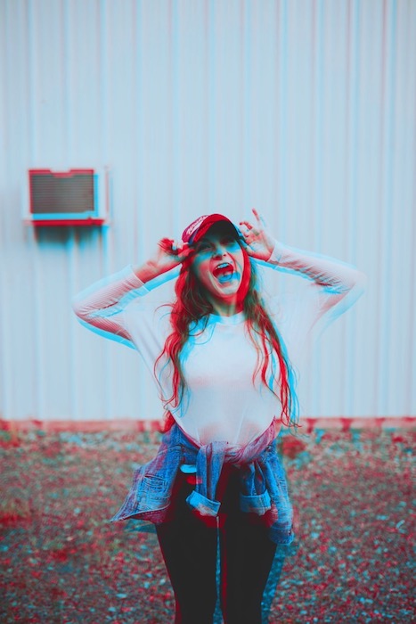 blurry photo of woman laughing wearing a white shirt and cap