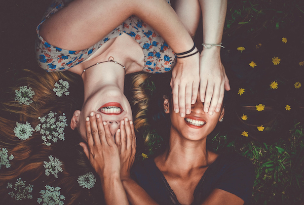 women covering each other's eyes and smiling