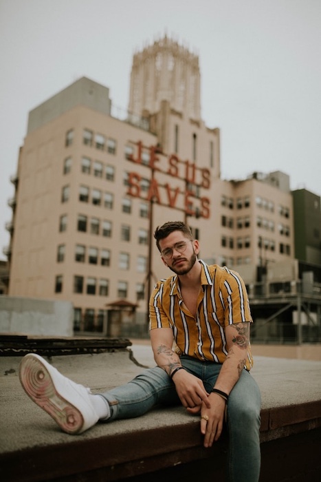 man sitting on rooftop in front of city skyline