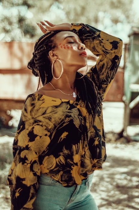 woman with long braids wearing a multi-colored shirt 