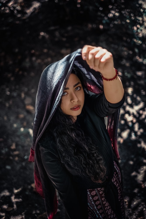 Picture of a woman holding a scarf up her head.