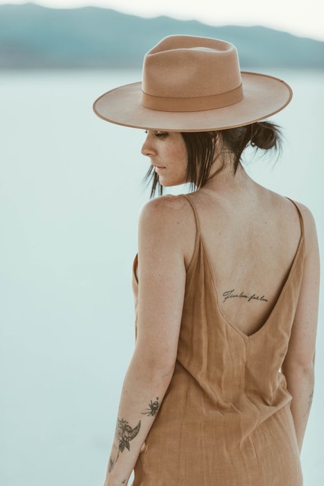 woman with tattoos in khaki hat and dress