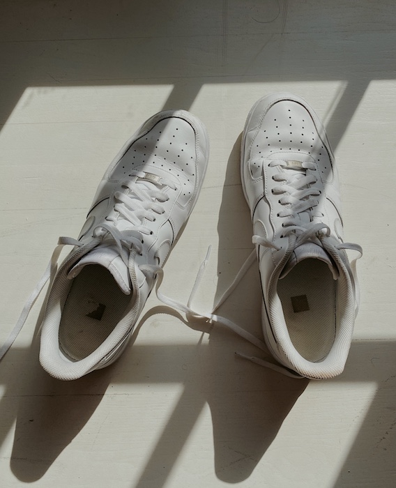white sneakers on a white surface with shadows cast over them