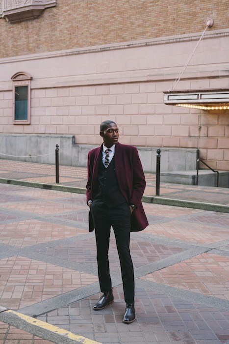 man wearing a suit standing on the sidewalk