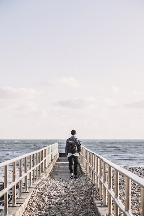 man with a backpack walking along a jetty