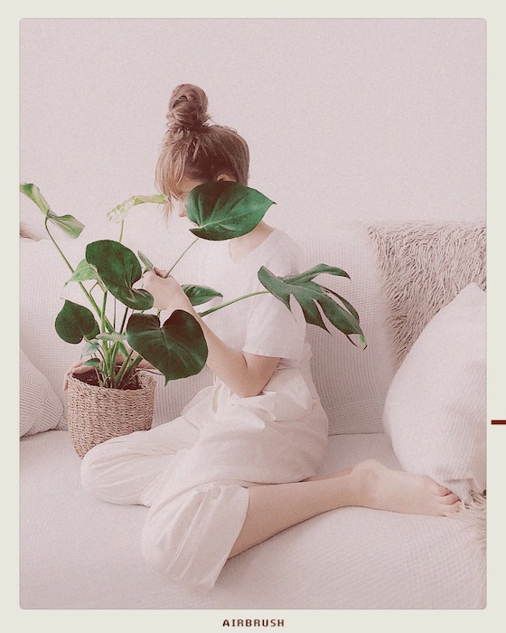 woman sitting on a white couch holding a plant