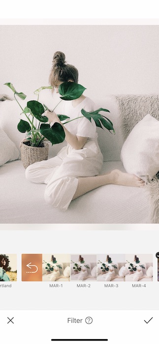 woman sitting on a white couch holding a plant