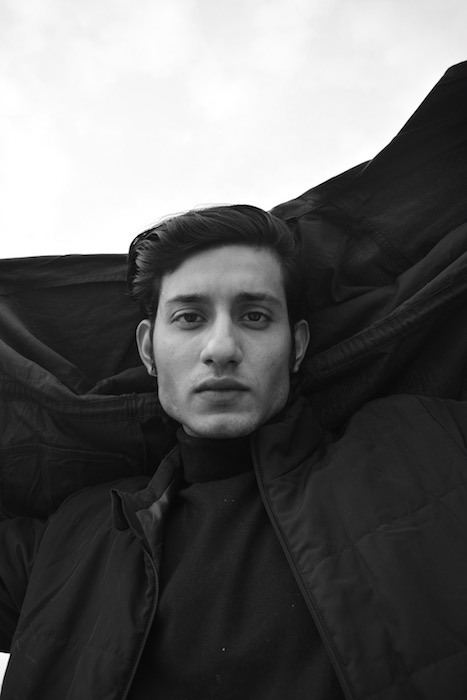 black and white photo of man with dark hair in front of black and white background