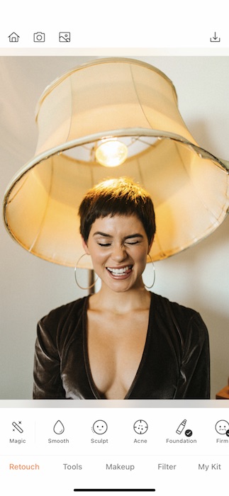 woman with a pixie haircut making a silly face while sitting under a lamp