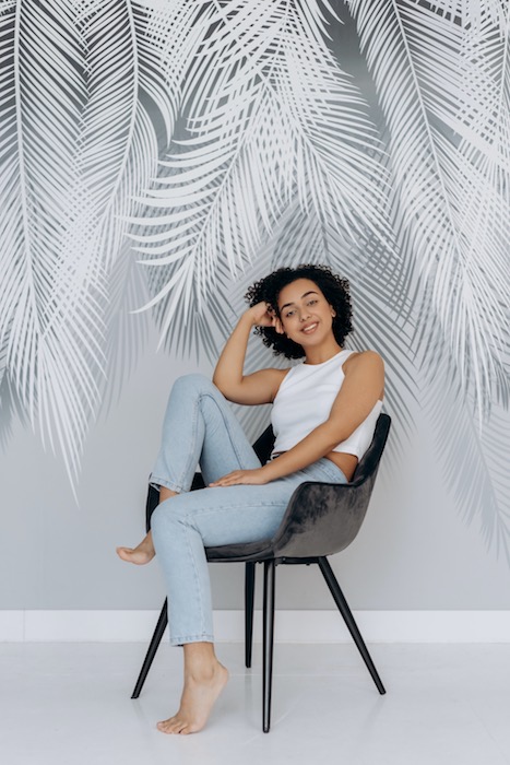 girl in blue jeans and white top with palm leaves