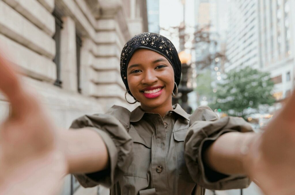 black woman wearing black head scarf taking a selfie in the city