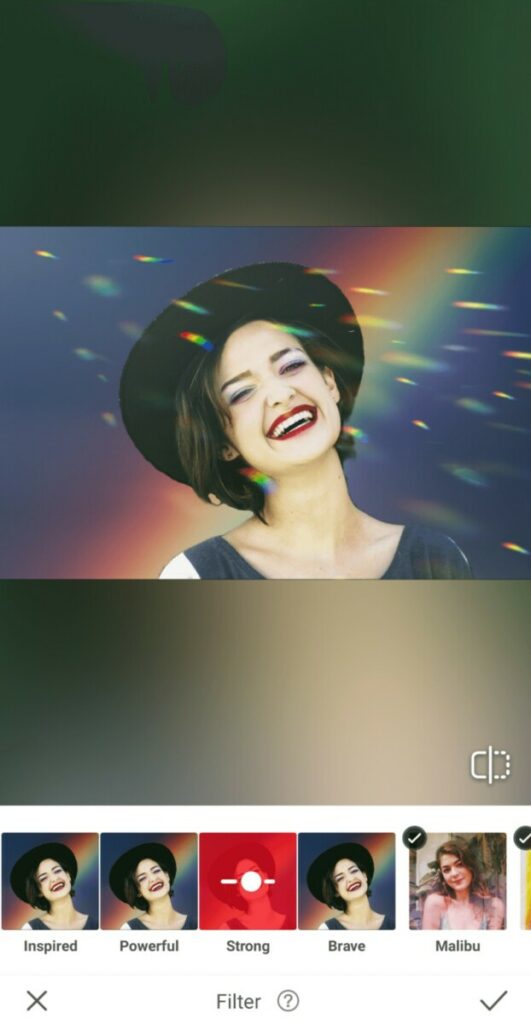 Pride edit of laughing woman wearing a hat in front of a rainbow background with light flares
