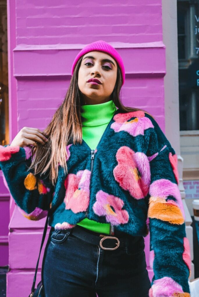 woman in brightly colored outfit standing in front of a pink wall