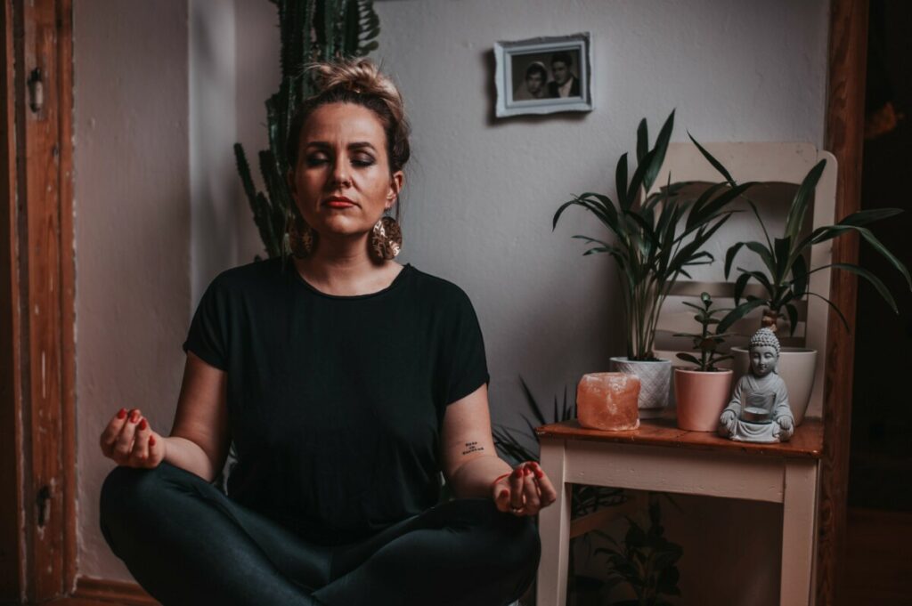 woman sitting and meditating next to plants