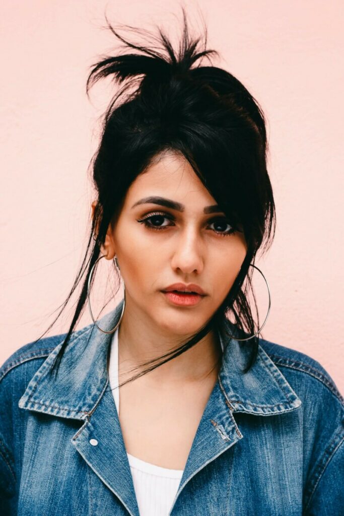 woman with wearing a denim jacket in front of a pink background