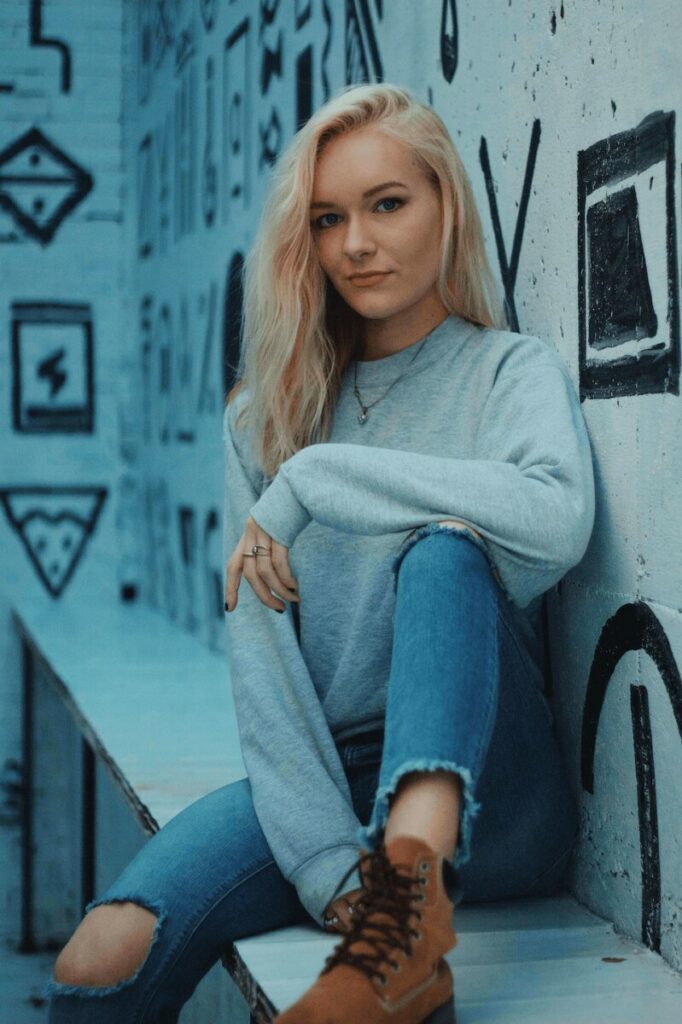 woman in grey sweater and jeans sitting in front of black and white mural