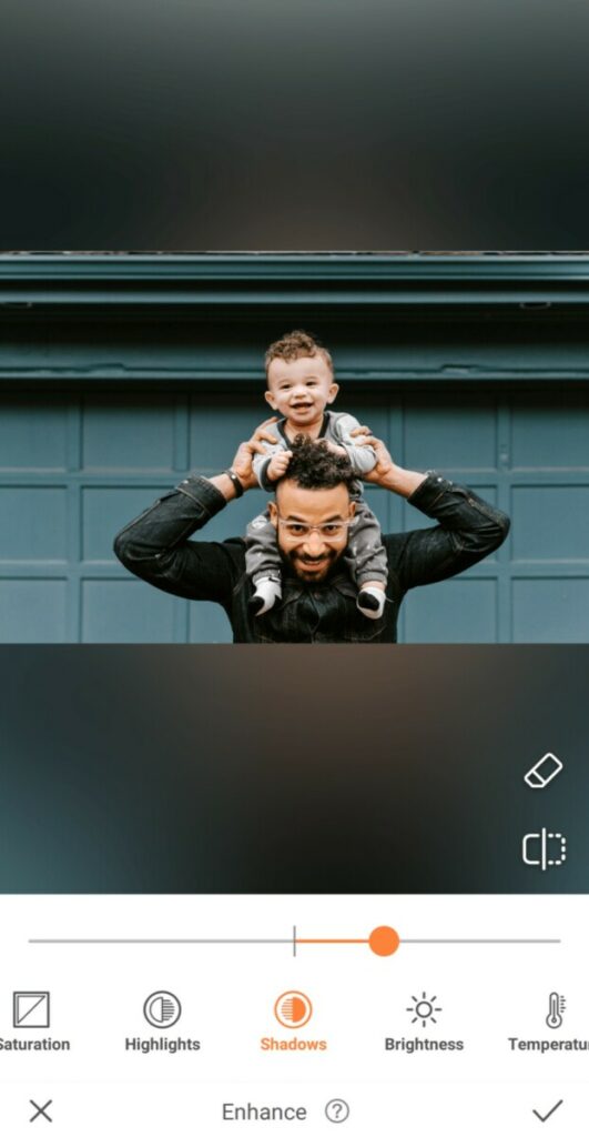 dad holding his toddler son on his shoulders in front of green garage wall