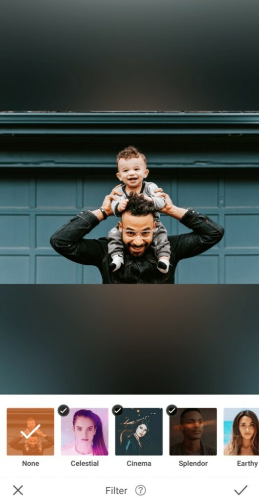 dad holding his toddler son on his shoulders in front of green garage wall
