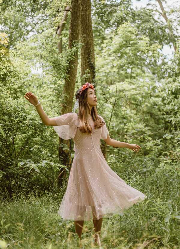 Garota com vestido rosa esvoaçante em uma floresta