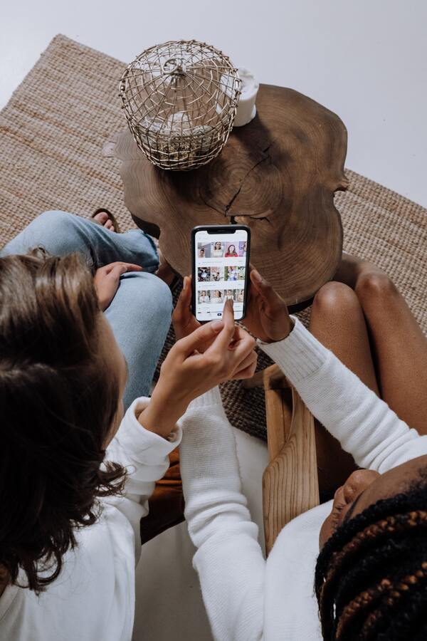 Duas garotas segurando um celular com várias fotos na tela