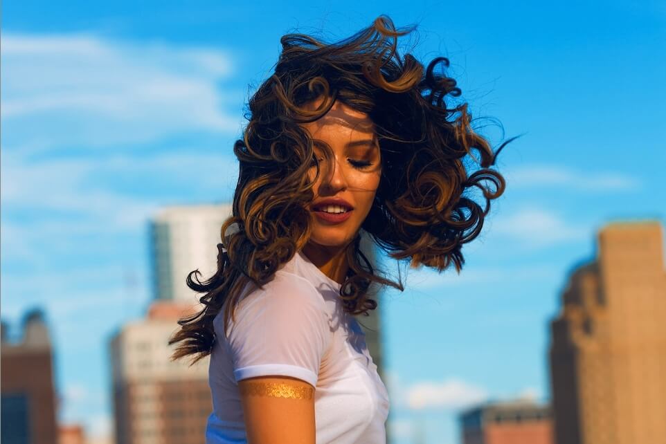 Leo Horoscope edit of woman with blowing hair against city backdrop