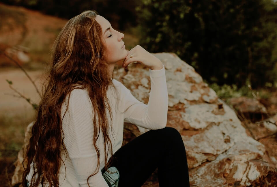 Sagittarius edit of a woman with long brown hair sitting on a rock
