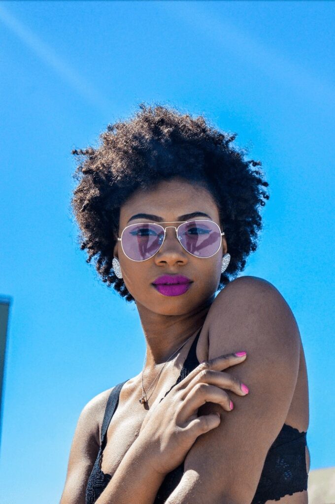 woman with afro wearing pink glasses