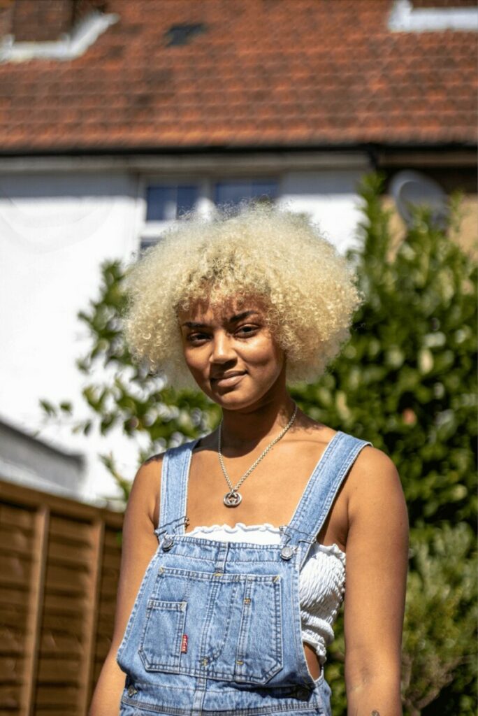 woman with curly blonde hair wearing overalls