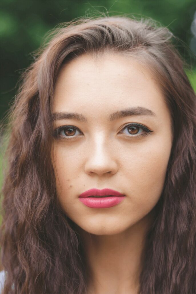 closeup of woman with brown hair wearing pink lipstick