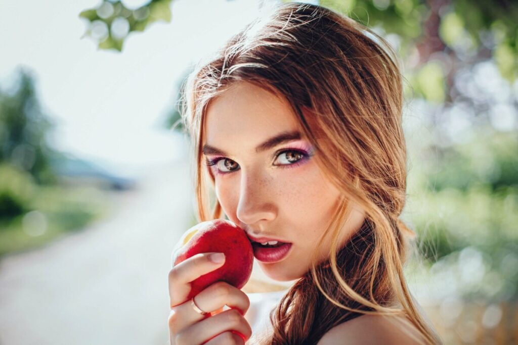 woman with Prism Makeup filter holding an apple