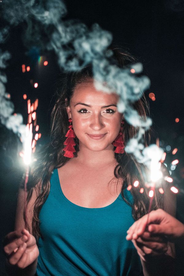 woman holds up sparkles at night