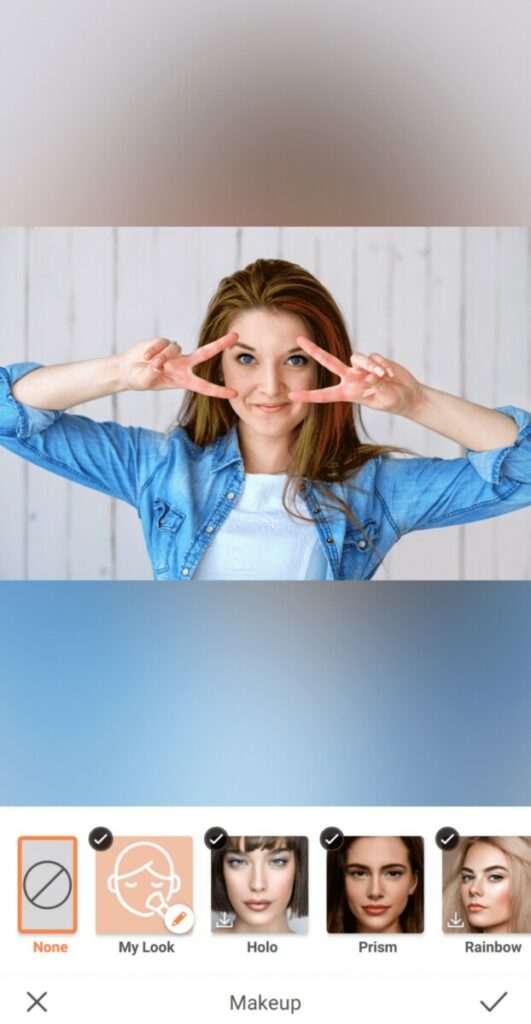 woman wearing chambray shirt making the peace sign over her eyes